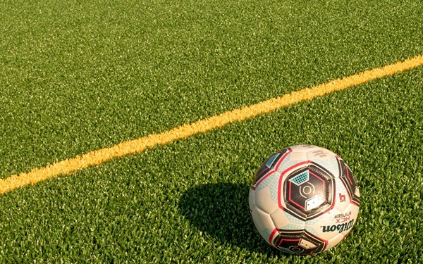 Why is artificial turf the first choice for professional football fields?